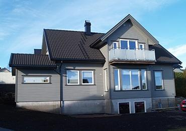Grå enebolig med balkong i glass